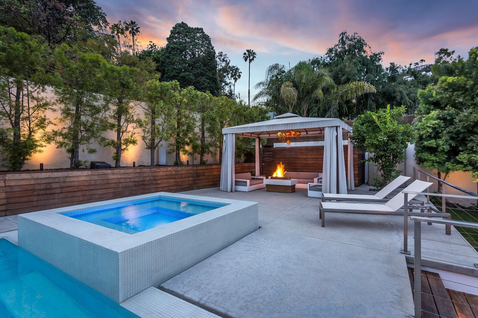 Resort-style backyard with pool, hot tub and dramatic sunset sky